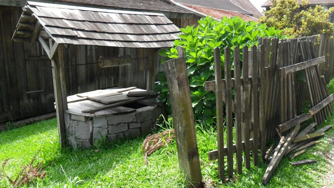 Kamenná studňa s dřevěnou střechou a plotem