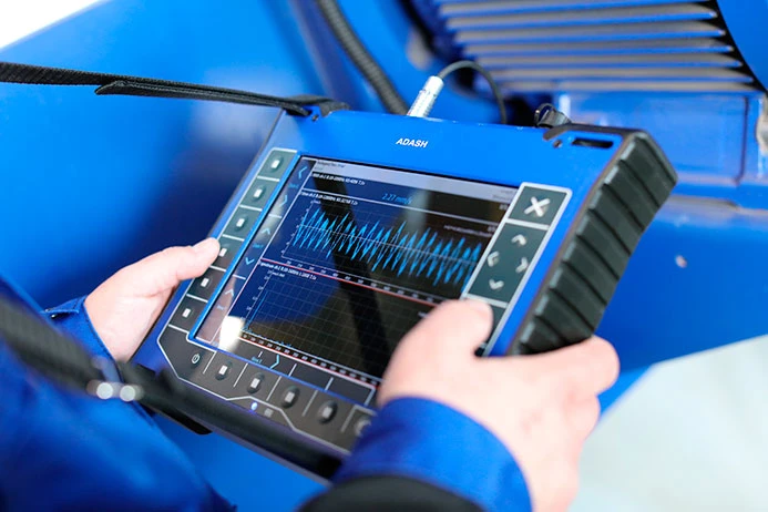 Technik používá přenosný analyzátor vibrací pro diagnostiku elektromotoru.
