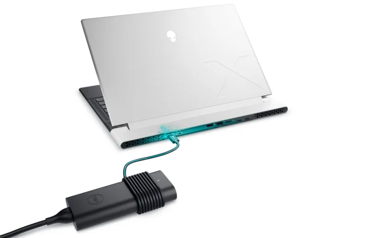 Bílý notebook nabíjen přes USB-C kabel s adaptérem značky Dell.