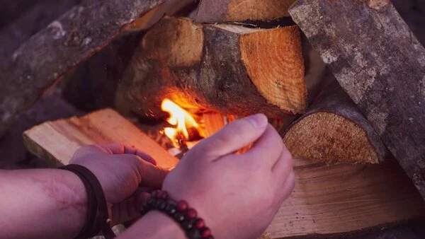 Ruční úprava hořícího dřeva v kamnech