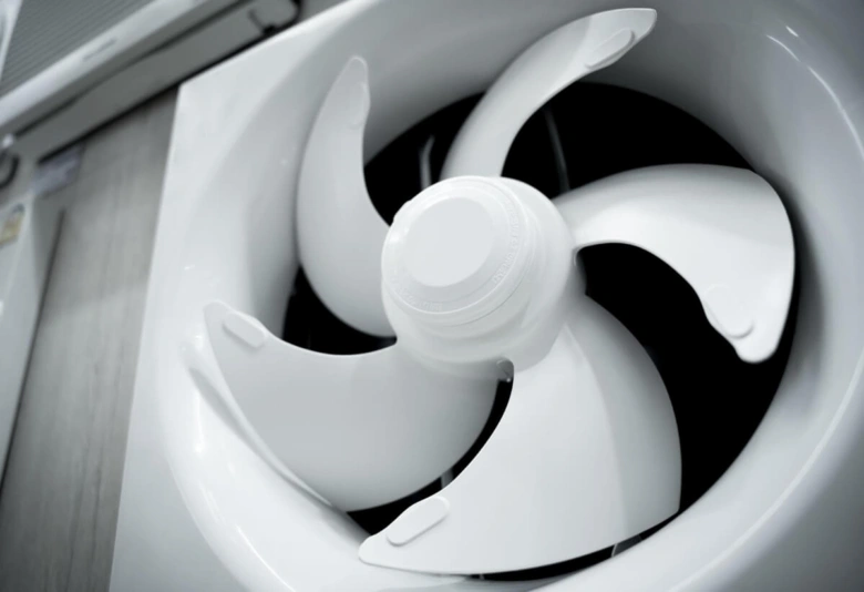 Bílý ventilátor pro větrání koupelny s viditelnými lopatkami.