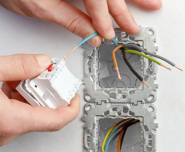 Ruční instalace dvoucestného spínače s připojením vodičů do elektrické krabice.