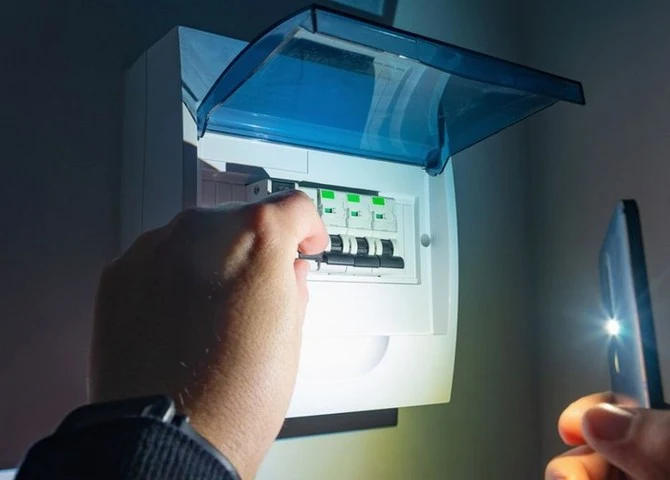 Ruce opravují elektrickou skříň při výpadku proudu.