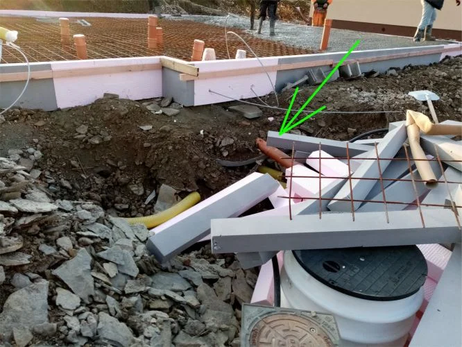 Staveniště s kanalizačním potrubím a izolací u základové desky.