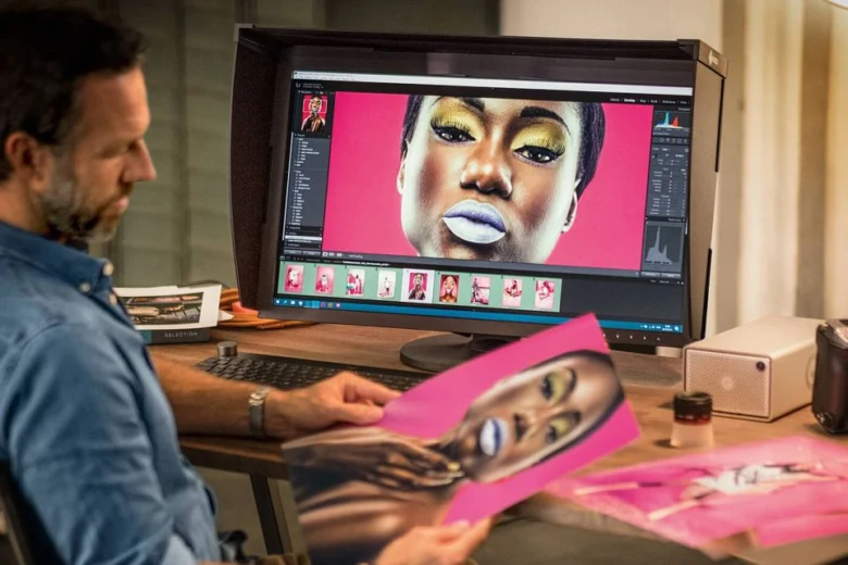Muž upravuje fotografii na monitoru v profesionálním studiu.