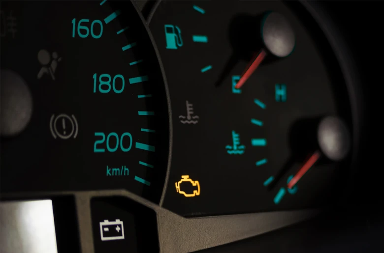 Rozsvícená kontrolka motoru na přístrojové desce automobilu.