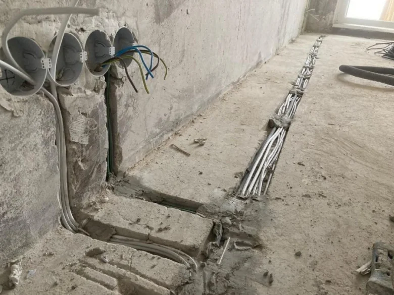 Instalace elektrického rozvodu s viditelnými kabely v betonu.