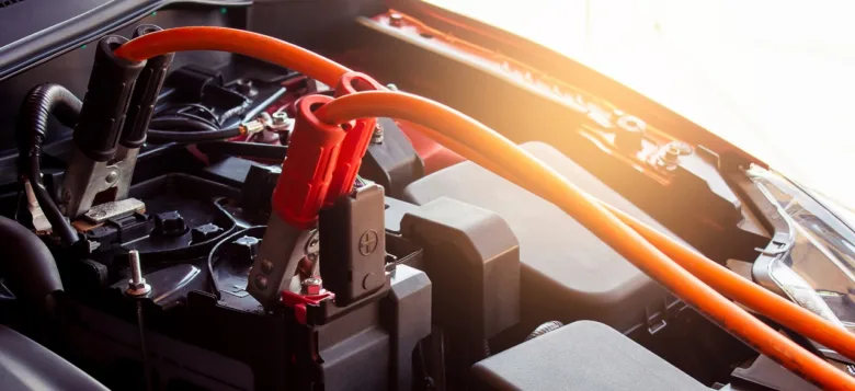 Oranžové kabely pro nabíjení automobilového akumulátoru pod kapotou.