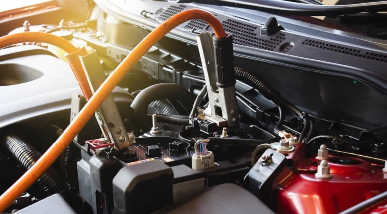 Připojené kabely pro nabíjení automobilové baterie pod kapotou.