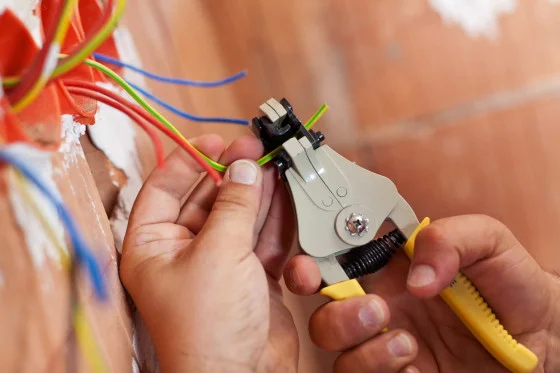 Elektrikář odstraňuje izolaci z drátů pomocí nástroje v zásuvce.