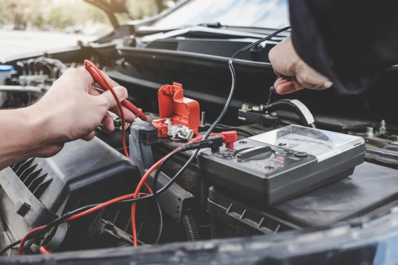 Testování polárnosti automobilové baterie multimetrem pod kapotou.