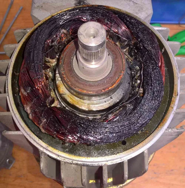 Spálený elektromotor s černými vinutím na rotoru.