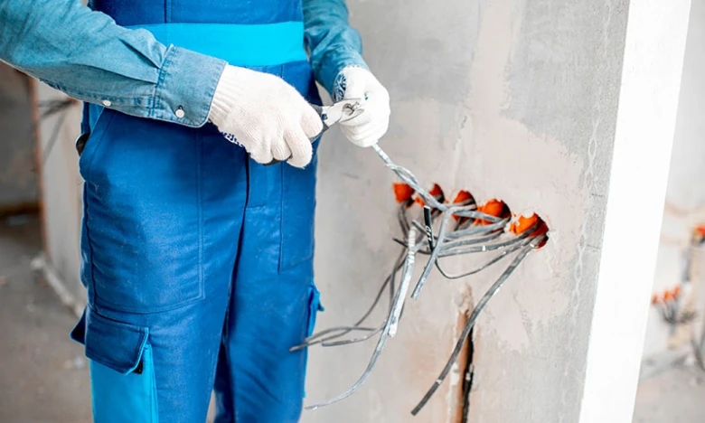 Elektrikář pracuje na instalaci zásuvek a vypínačů v bytě.