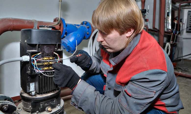 Elektrikář opravuje poškozený elektromotor průmyslového čerpadla.