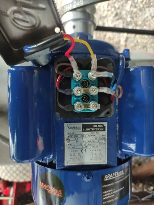 Otevřený elektromotor s viditelnými vodiči a pojistkovým blokem.