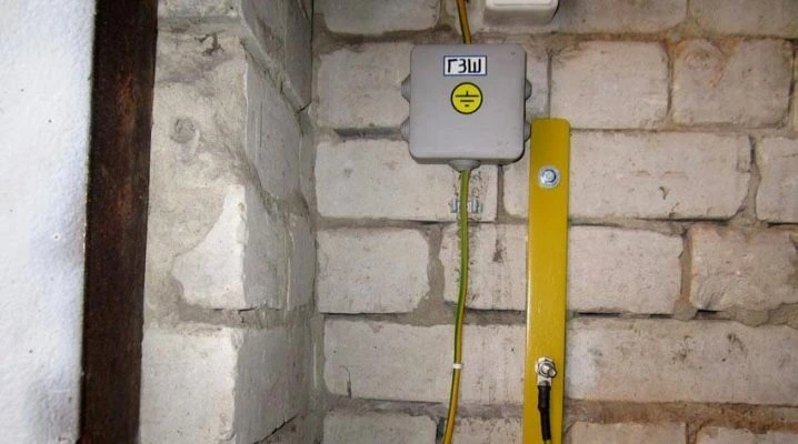 Zemní krabice s žlutým kabelem na cihlové zdi pro uzemnění kotla.