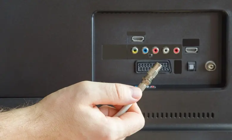 Ruka připojuje anténní kabel k televizoru pro naladění kanálů.