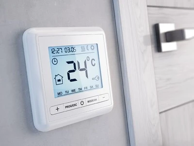 Digitální termostat na zdi s nastavenou teplotou 24 stupňů Celsia.