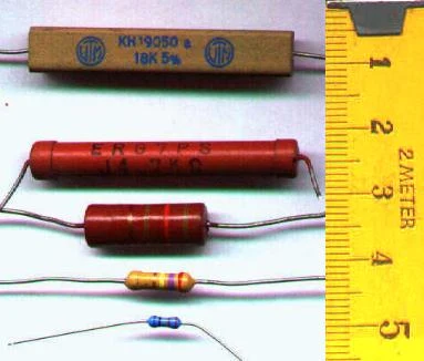 Různé typy elektronických rezistorů s měřicí páskou pro porovnání velikosti.