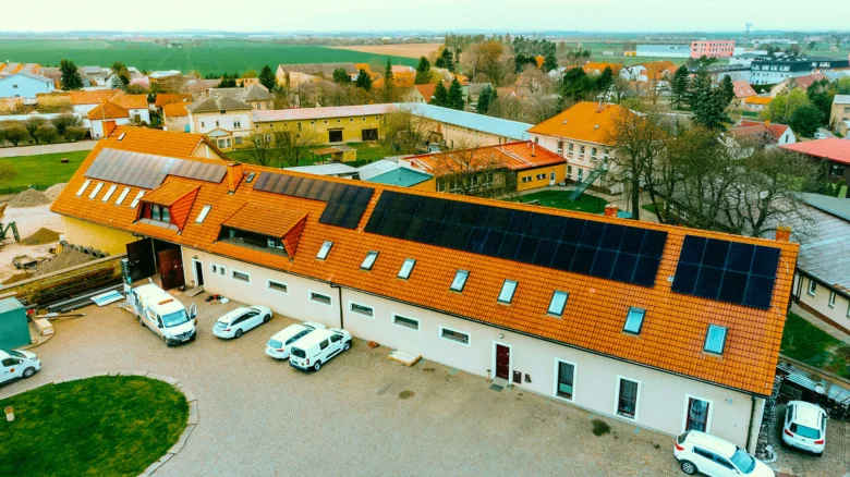 Vzdušný pohled na budovu s solárními panely na střechách.