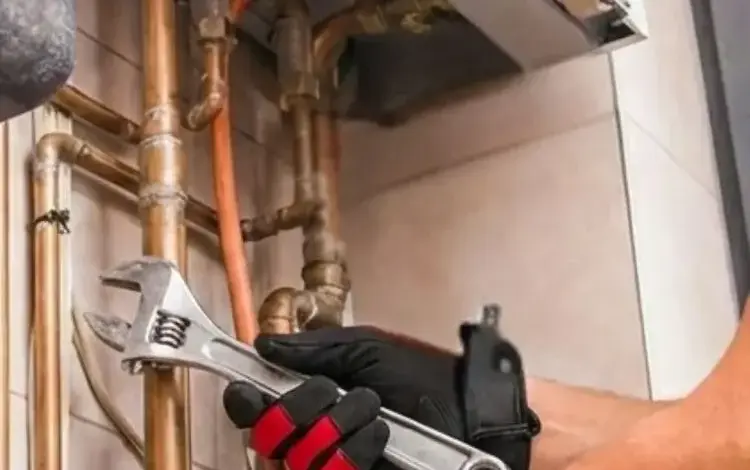 Instalatéř opravuje potrubí s klíčovým nástrojem.