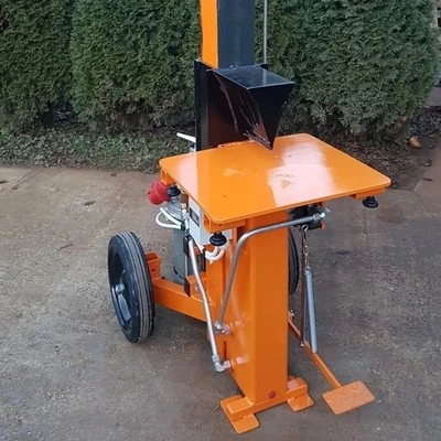 Oranžová elektromotorová štípačka dřeva s koly venku.