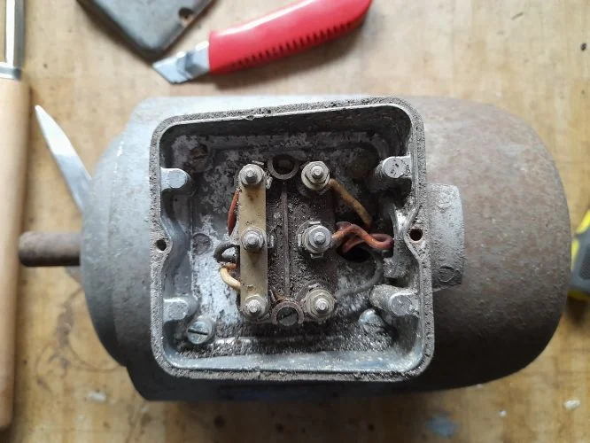 Otevřený terminál elektromotoru s viditelnými vodiči pro přepojení.