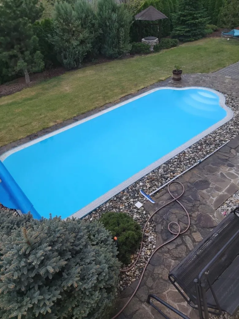 Venkovní bazén s částečně odvinutou plachtou na trávníku.