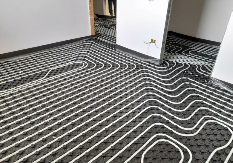 Instalace potrubí podlahového vytápění na izolační rohož v interiéru.