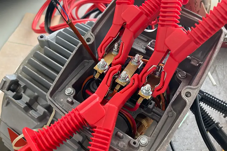 Červené měřicí svorky připojené k elektrickým terminálům v ovladači.