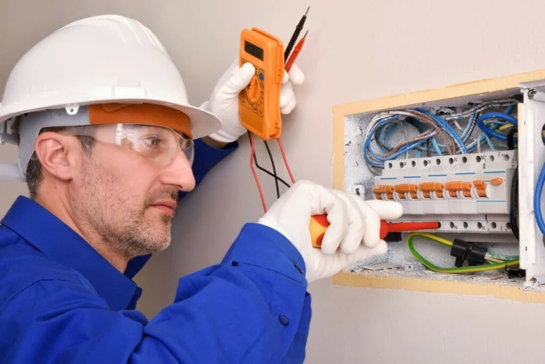 Elektrikář měří napětí v rozvaděči s multimetrem.