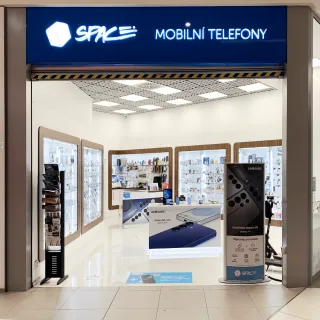 Vnitřek prodejny mobilních telefonů s výlohou a reklamními standy.