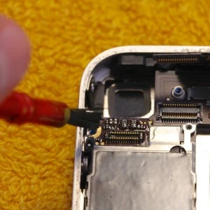 Čistění elektrických kontaktů v mobilním telefonu nástrojem s červenou rukojetí.