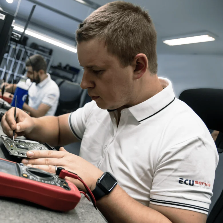 Mechanik opravuje elektroniku vozidla pomocí multimetru v dílně.