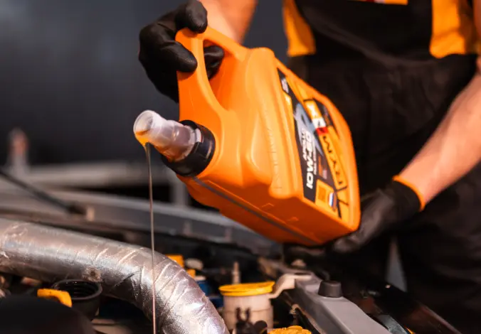 Mechanik nalévá olej do motora při údržbě automobilu.