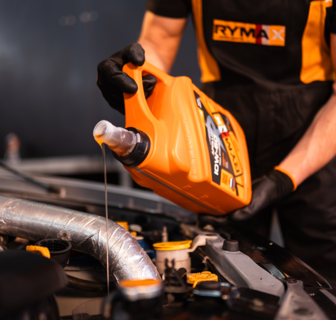 Mechanik nalévá olej do motora při údržbě automobilu.