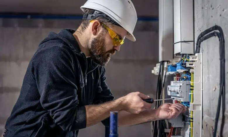 Elektrikář pracuje na rozvaděči s jističi.