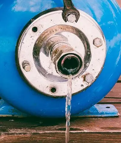 Modrá expanzní nádrž s únikem vody z ventilu.