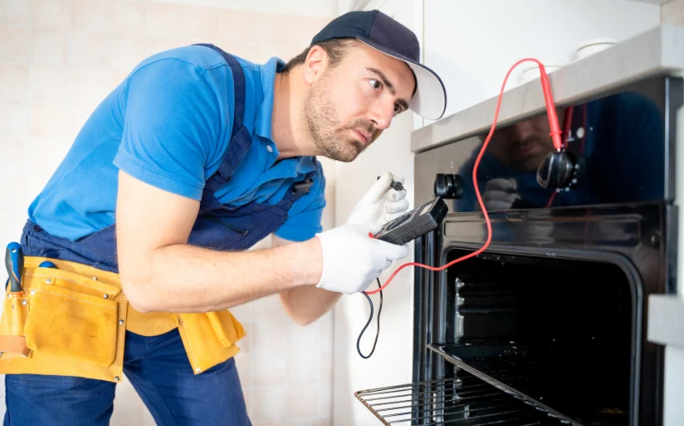Technik měří elektrickou spotřebu troub pomocí multimetru.