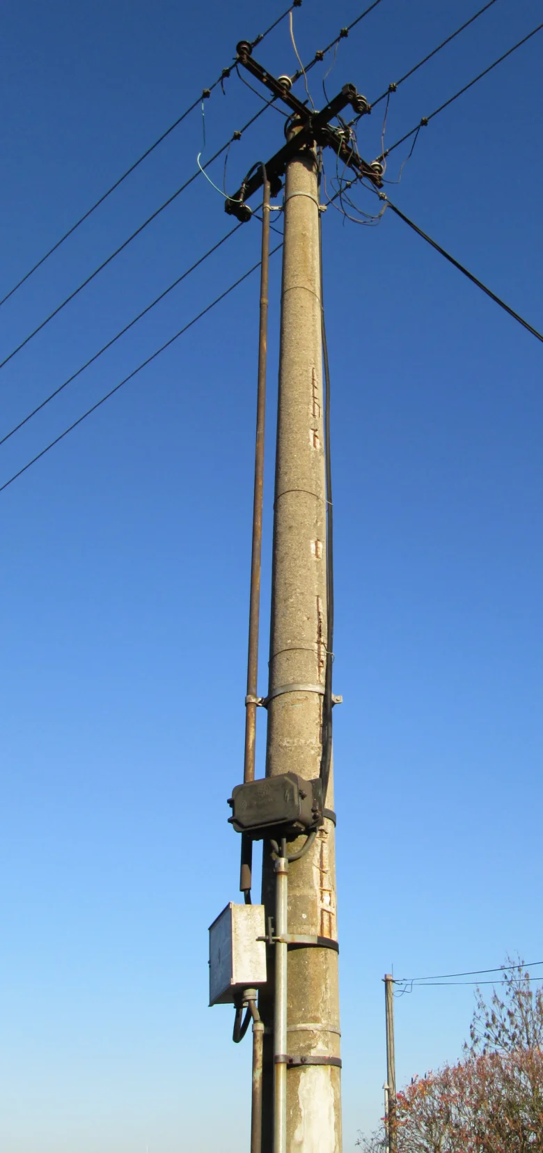 Konkrétní elektrický sloup s vedením na modré obloze.