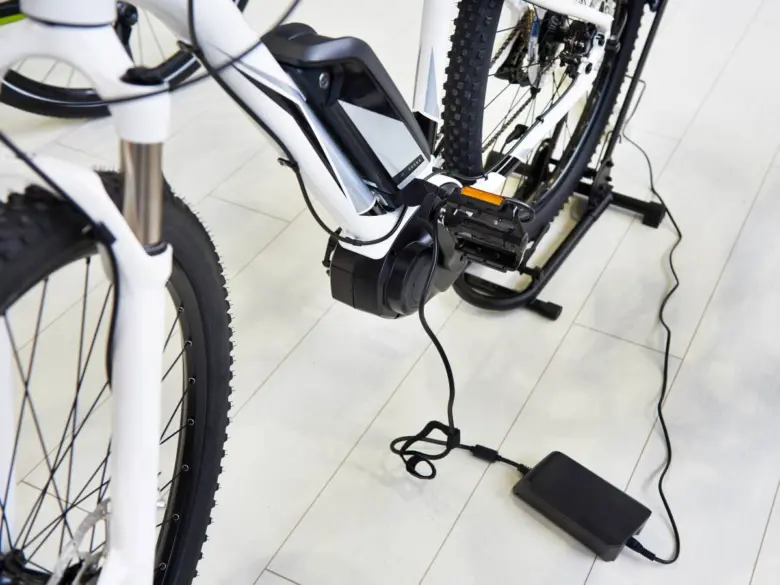 Bílá elektrobikla s nabíjenou baterií na podlaze.