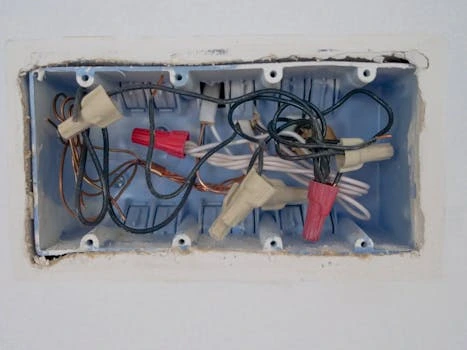 Modrá elektrická krabička s dráty pro sériové zapojení zásuvek.