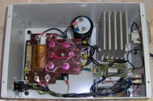 Vnitřní zapojení nabíječky s elektronickými součástkami v kovovém pouzdře.