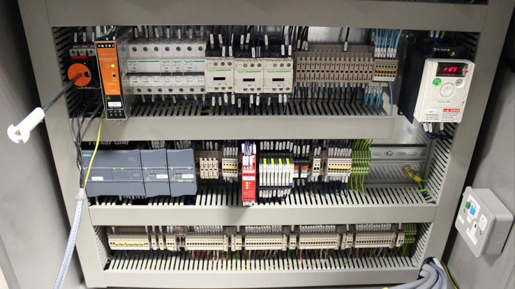 Průmyslový elektrický rozvaděč s jističi a terminály.