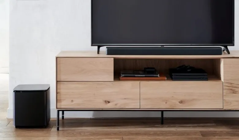 Soundbar pod televizorem na dřevěném stole v obývacím pokoji.