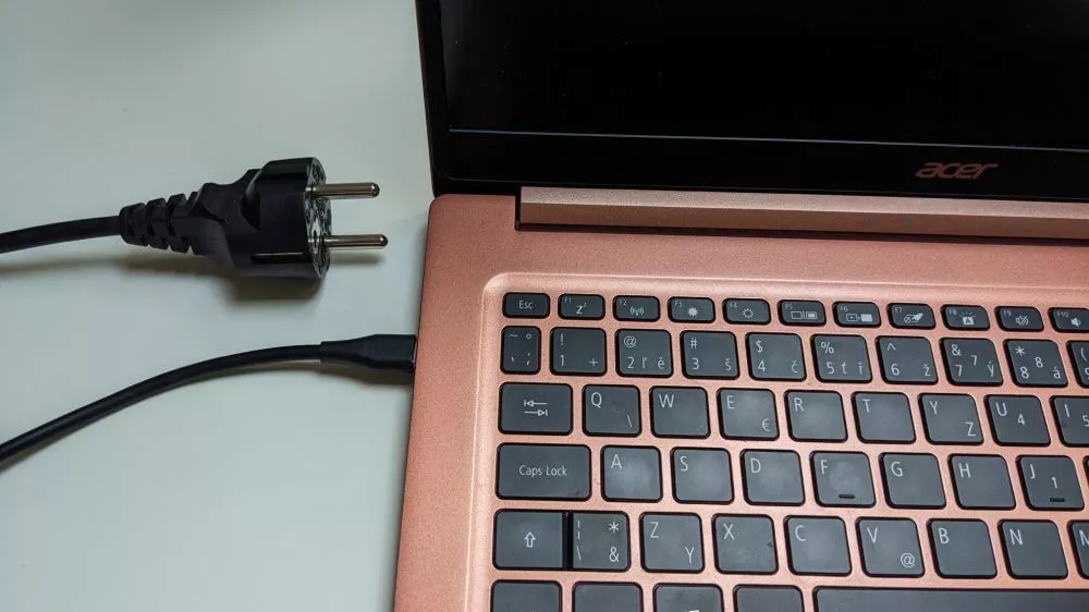Růžový notebook Acer s odpojeným nabíjecím kabelem vedle něj.