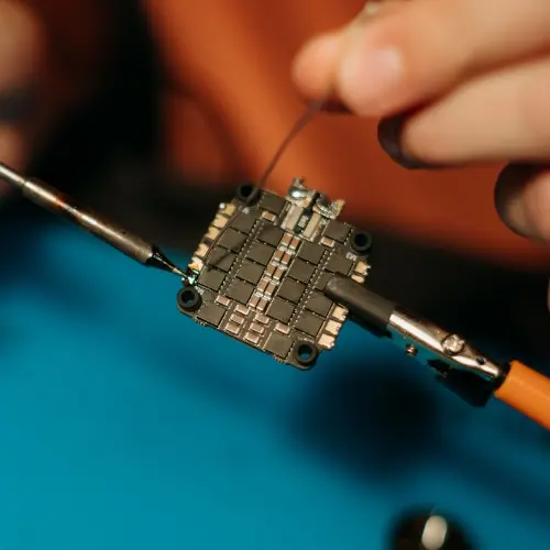 Pájení elektronického obvodu pomocí železa a pinzety.