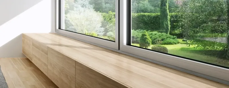 Dřevěný parapet u plastového okna s výhledem na zahradu.