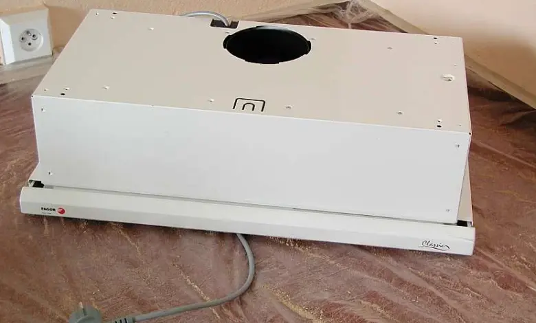 Bílá digestoř připravená k instalaci na kuchyňskou linku.