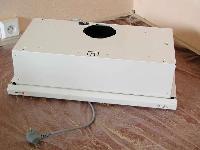 Bílá digestoř připravená k instalaci na kuchyňskou linku.